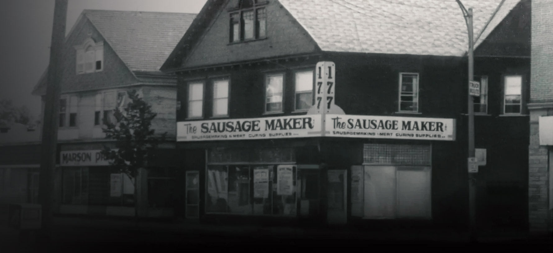 Black and white image of a building with 'The Sausage Maker' sign.